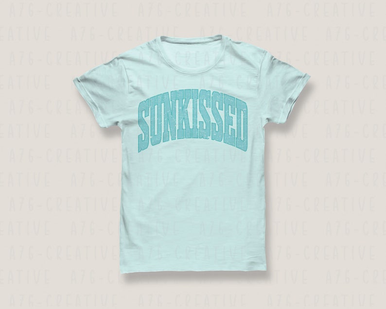 May include: A light blue t-shirt with the word "SUNKISSED" printed in a blue, distressed font.