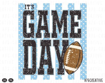May include: A graphic design featuring the text IT'S GAME DAY in distressed black block letters. The background consists of vertical light blue stripes with white polka dots. A brown American football with white laces is positioned on the right.