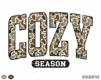 May include: A graphic design featuring the word "COZY" in large, distressed letters with a camouflage pattern in shades of brown, green, and tan. Below, the word "SEASON" is in a black, distressed banner.