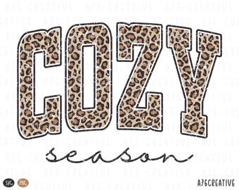 May include: A graphic design featuring the words "COZY SEASON" in a bold, distressed font. The word "COZY" is filled with a leopard print pattern, while "season" is in a cursive font. The design is on a white background.