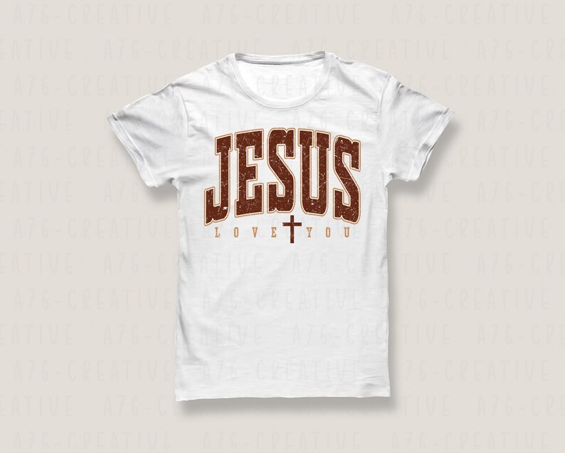 Pode incluir: Camiseta branca com um gr&aacute;fico marrom desbotado que diz "JESUS LOVE YOU" com uma pequena cruz entre as palavras "LOVE" e "YOU".