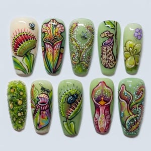 May include: A set of ten press-on nails featuring detailed hand-painted illustrations of various carnivorous plants, including Venus flytraps and pitcher plants, with vibrant green, red, and purple tones, accented by small insects like bees and ants.