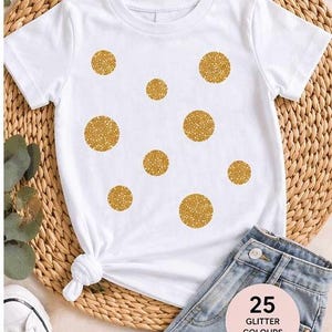 May include: White t-shirt with gold glitter polka dots. The image text reads "POLKA DOTS GLITTER IRON-ON SIRCLES MIXED SIZES 0.5" - 2" 12 PACK". The image also shows blue jeans and white trainers. 25 glitter colours are available.