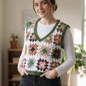 Puede incluir: Un chaleco de ganchillo con cuello en V, con un diseño de patchwork de cuadrados blancos, verdes, marrones y rosas. Los bordes están ribeteados con hilo verde. El chaleco se lleva sobre una camiseta blanca de manga larga y vaqueros negros.
