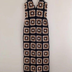 May include: A long, sleeveless crochet dress with a V-neckline. The dress is made of black, white and brown yarn and features a geometric pattern.