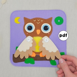 May include: A felt owl on a purple square with a yellow moon and green circle. The owl has brown and tan feathers, large blue eyes, and is perched on a brown branch with green leaves. The word "pdf" is in a white circle.