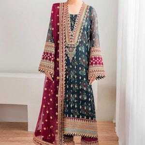 May include: An elegant teal and burgundy embroidered salwar kameez ensemble. The long-sleeved tunic features intricate gold detailing around the neckline, cuffs, and hem. A matching burgundy dupatta and trousers complete the outfit, suitable for special occasions.