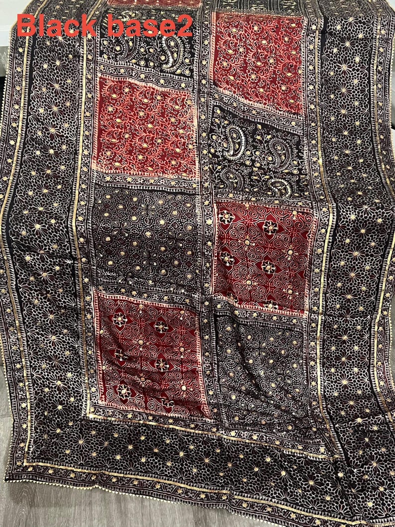 K&ouml;nnte beinhalten: Schwarzer Stoff mit einem Patchwork-Design mit roten und schwarzen Quadraten. Die Quadrate sind mit goldfarbenen Verzierungen und Mustern verziert. Der Text "Black base 2" ist in der oberen linken Ecke sichtbar.