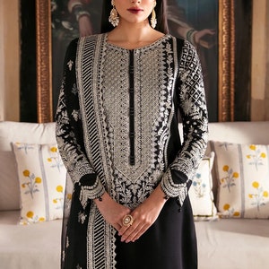 May include: A black long-sleeved dress with silver embroidery and a matching dupatta. The dress has a round neckline and a button closure. The model is wearing a gold headpiece and earrings.