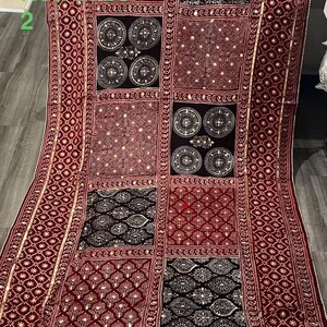 K&ouml;nnte beinhalten: Burgunderfarbenes Textil mit Patchwork-Design. Das Textil weist verschiedene Muster auf, darunter geometrische Formen, florale Motive und kreisf&ouml;rmige Designs. Goldfarbene Verzierungen und Bord&uuml;ren sorgen f&uuml;r Details. Der Text "Red base 2" ist sichtbar.