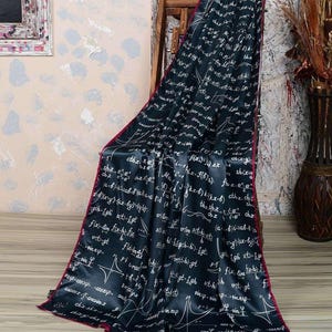 May include: A black satin scarf with a white print of mathematical equations and graphs. The scarf has a red border and is draped over a wooden chair.