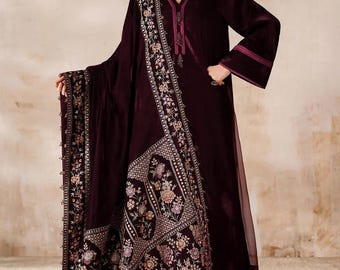May include: A rich burgundy velvet outfit with detailed floral embroidery. The set comprises a long-sleeved tunic, a matching scarf, and a shawl with elaborate patterns. The design combines traditional and modern elements, ideal for special events and celebrations.
