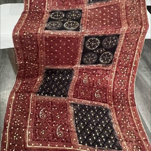 K&ouml;nnte beinhalten: Rotes Textil mit Patchwork-Design. Die Quadrate weisen komplizierte Muster auf, darunter Paisley- und geometrische Formen, mit goldenen Akzenten. Der Text "Red base 1" ist sichtbar.