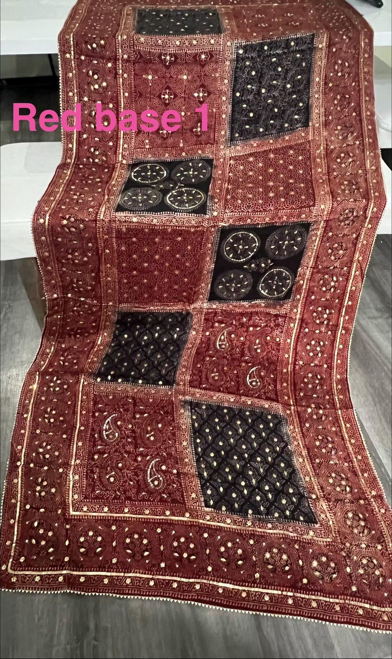 K&ouml;nnte beinhalten: Rotes Textil mit Patchwork-Design. Die Quadrate weisen komplizierte Muster auf, darunter Paisley- und geometrische Formen, mit goldenen Akzenten. Der Text "Red base 1" ist sichtbar.