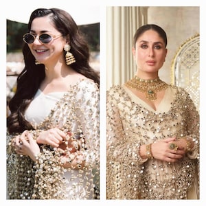 May include: Two women wearing ornate, embellished garments. One wears sunglasses and gold earrings, the other a gold necklace and bracelet. Both outfits feature intricate detailing with reflective elements, suggesting formal wear or bridal attire.