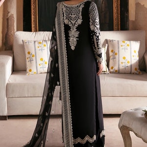 May include: A black long-sleeved dress with silver embroidery and a matching black sheer dupatta. The dress has a scalloped hemline and the dupatta has a silver border.