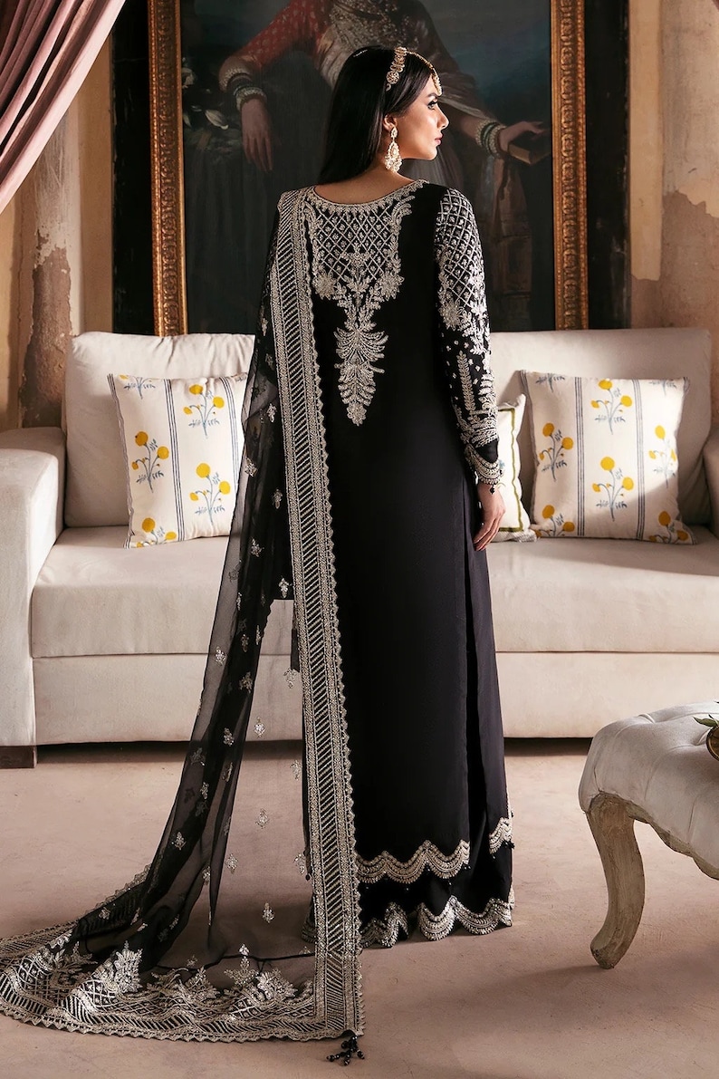 May include: A black long-sleeved dress with silver embroidery and a matching black sheer dupatta. The dress has a scalloped hemline and the dupatta has a silver border.