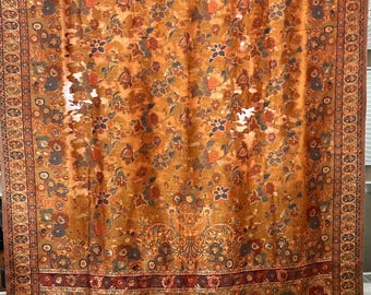 May include: A large, rectangular textile featuring a detailed floral design in orange, brown, and blue hues. The pattern includes a decorative border and a central floral field. The fabric appears to be lightweight, with a delicate appearance. The textile is likely a curtain or a shawl.