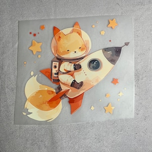 Könnte beinhalten: Ein süßer orangefarbener Fuchs, der einen Astronautenanzug trägt und mit einer Rakete durch den Weltraum fliegt. Der Fuchs lächelt und trägt einen weißen Helm. Die Rakete ist weiß mit einer roten Flamme und einem schwarzen Fenster. Im Hintergrund sind gelbe Sterne zu sehen.