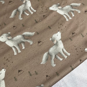 Könnte beinhalten: Brauner Stoff mit einem sich wiederholenden Muster aus grauen Wölfen, die zum Mond heulen. Die Wölfe sind von kleinen grünen Bäumen und braunen Bergen umgeben.