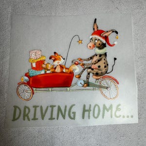 Könnte beinhalten: Ein roter Wagen, der von einem Esel gezogen wird, der einen Weihnachtsmann-Hut trägt. Ein Fuchs und eine Maus fahren im Wagen. Der Wagen ist mit verpackten Geschenken gefüllt. Der Text "DRIVING HOME..." befindet sich unter dem Wagen.