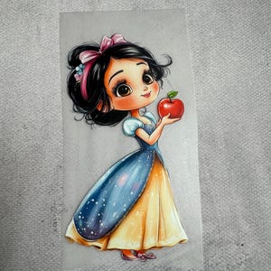 Könnte beinhalten: Aufkleber mit einer Cartoon-Illustration einer jungen Frau in einem blau-gelben Kleid, die einen roten Apfel hält. Die Frau hat schwarzes Haar, eine rosa Schleife und einen süßen Ausdruck. Das Kleid hat ein blaues Oberteil mit weißen Punkten und einen gelben Rock.