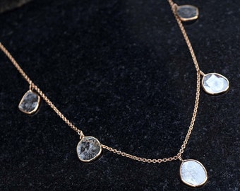 Puede incluir: Un delicado collar de cadena de oro con cinco colgantes de piedras preciosas transparentes facetadas.