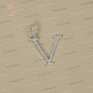Peut inclure: Un pendentif en argent en forme de lettre V, incrusté de petits diamants clairs.