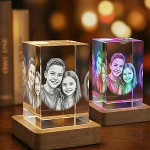 May include: Two illuminated crystal photo blocks, each displaying a portrait of three smiling children. The blocks sit on wooden bases. One block is in grayscale, the other has a colorful, rainbow-like glow.