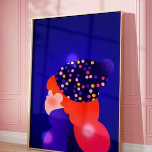 May include: A framed art print depicting a stylized figure with red hair and a polka-dot hat against a dark blue backdrop. The artwork is in a gold frame, leaning against a pink wall, with a wooden floor.