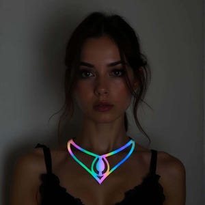 May include: A woman wearing a glowing, iridescent necklace. The necklace has a geometric design with a central teardrop shape and a rainbow gradient of colors. The woman is wearing a black top.