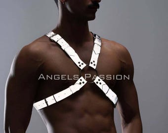 May include: A reflective silver harness with a circular chest ring and strap design. The text "ANGELS PASSION" is printed on the chest. The harness is worn over bare skin. The person is wearing black pants.