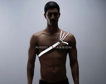 May include: A white leather harness with a silver buckle and rings. The harness is worn on the chest and shoulder of a person.