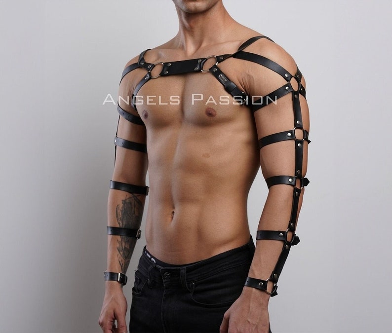 May include: Black leather body harness with straps and metal ring accents. The harness includes shoulder straps, armbands, and wristbands. The text "ANGELS PASSION" is visible on the chest.