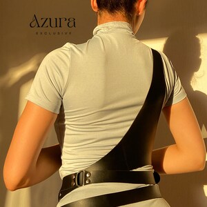 Puede incluir: Un body de color azul claro con un arn&eacute;s de cuero negro. El arn&eacute;s presenta una correa ancha en el pecho y un cintur&oacute;n alrededor de la cintura con una hebilla plateada. El logotipo de Azura Exclusive es visible.