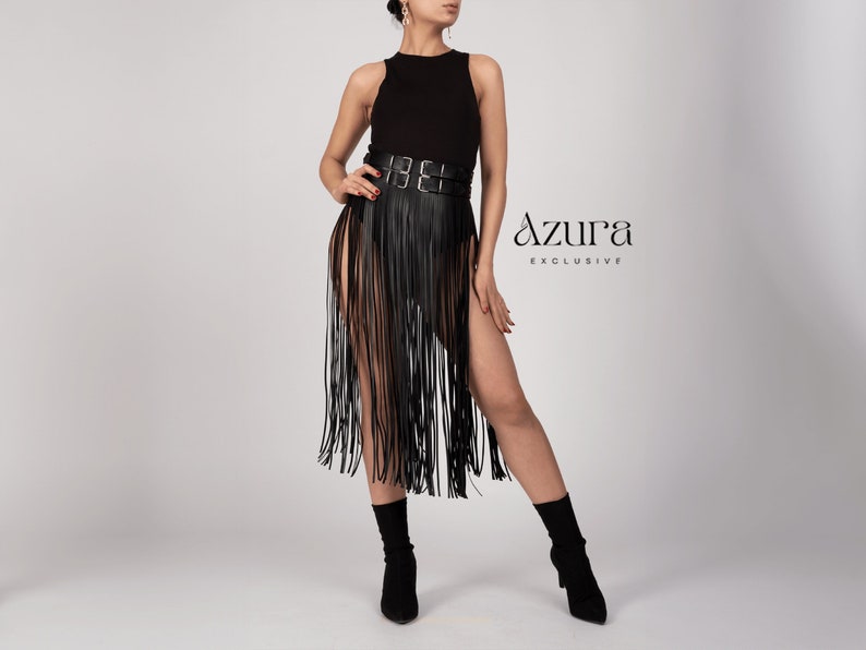 May include: Black fringe skirt with a high waist belt. The skirt has long, vertical fringe and high slits on both sides. The text "Azura Exclusive" is visible on the right side of the image.