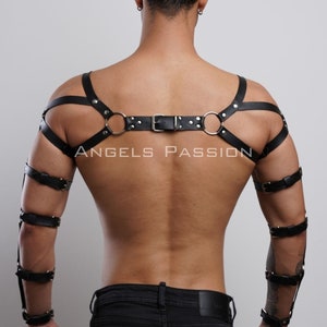 May include: Black leather harness with straps, metal rings, and buckles. The text "ANGELS PASSION" is visible on the back. The harness includes arm cuffs and shoulder straps, creating a bold and edgy look.
