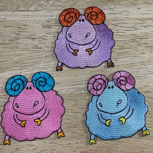 May include: Three embroidered iron-on patches of cartoon rams with different coloured fur and horns. The rams are pink, purple and blue.