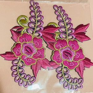 May include: Two pink and green embroidered floral appliques with a leafy design. The appliques are ideal for adding a touch of elegance to clothing, bags, or home decor projects.
