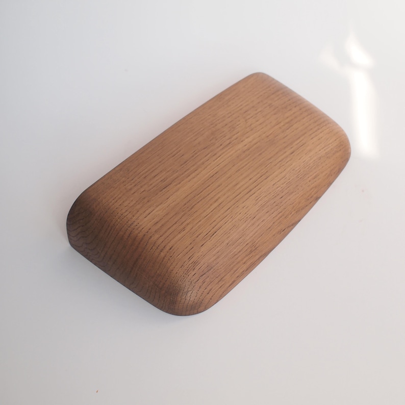 K&ouml;nnte beinhalten: Ein rechteckiges Holztablett mit abgerundeten Ecken und einer glatten, nat&uuml;rlichen Oberfl&auml;che. Die Holzmaserung ist deutlich sichtbar und verl&auml;uft horizontal &uuml;ber die Oberfl&auml;che des Tabletts. Die Kanten sind abgerundet und weich geformt.
