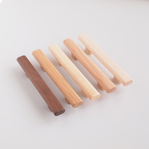 May include: Six wooden cabinet pulls in various shades of brown, from dark walnut to light oak. The pulls are all rectangular with rounded edges.