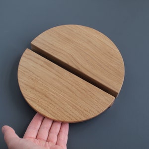 Puede incluir: Una manija de puerta de madera hecha de dos piezas de medio círculo que encajan entre sí. La manija es de madera marrón claro y tiene un acabado liso.