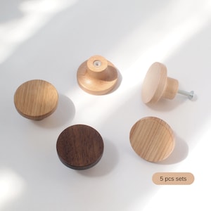 May include: Set of five wooden knobs in various shades of brown. The knobs are round and have a smooth finish. They are perfect for adding a touch of rustic charm to any room.