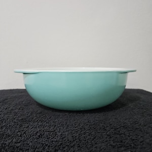 May include: A light blue ceramic mixing bowl with a white rim. The bowl is sitting on a black surface.