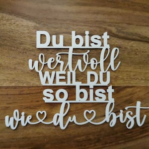 Könnte beinhalten: Weißes Holzschild mit dem Text "Du bist wertvoll weil du so bist wie du bist" mit zwei Herzen in der Mitte.