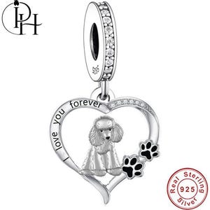 May include: A silver charm featuring a poodle within a heart, inscribed with "I love you forever". The charm includes paw prints and a ring adorned with clear stones. Crafted from 925 sterling silver.