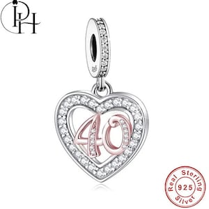 May include: A sterling silver charm with a heart-shaped pendant. The pendant features the number "40" in rose gold, encrusted with small clear stones, and is surrounded by a halo of clear stones. The charm has a loop for attaching to a bracelet.