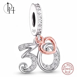 Op de afbeelding: Een bedel van sterling zilver in de vorm van het getal 30, versierd met heldere steentjes en een klein roségoudkleurig hartje. De bedel heeft een oogje bezet met heldere steentjes en is gestempeld met S925, wat wijst op sterling zilver.