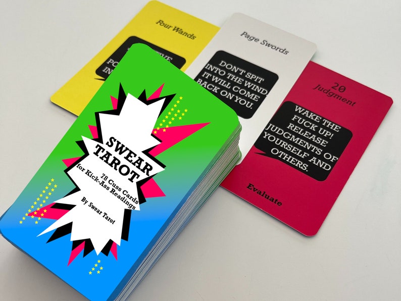 May include: A deck of 78 cards called "Swear Tarot" for "Kick-Ass Readings". The cards are green, blue, pink, and yellow with black and white text. The text on the front of the deck reads "Swear Tarot" and "78 Cuss Cards for Kick-Ass Readings".