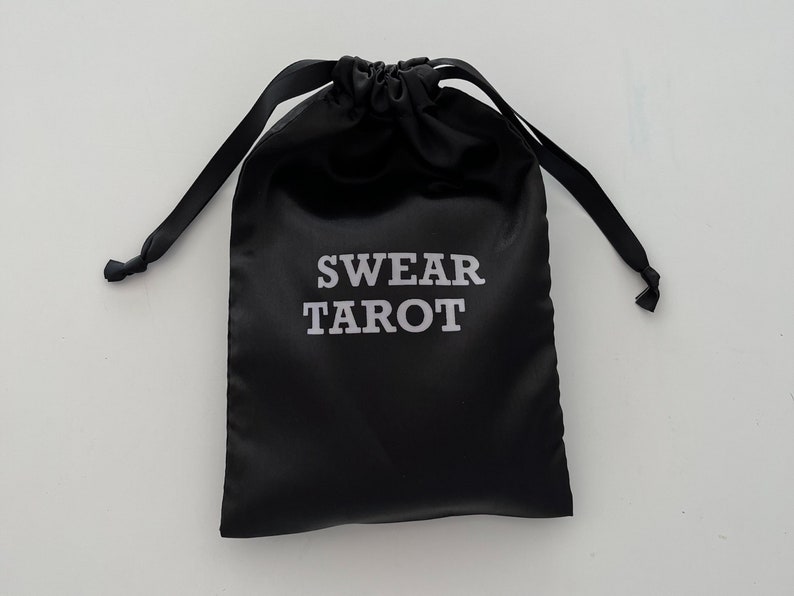 May include: A black satin drawstring bag with the text "SWEAR TAROT" printed in white.